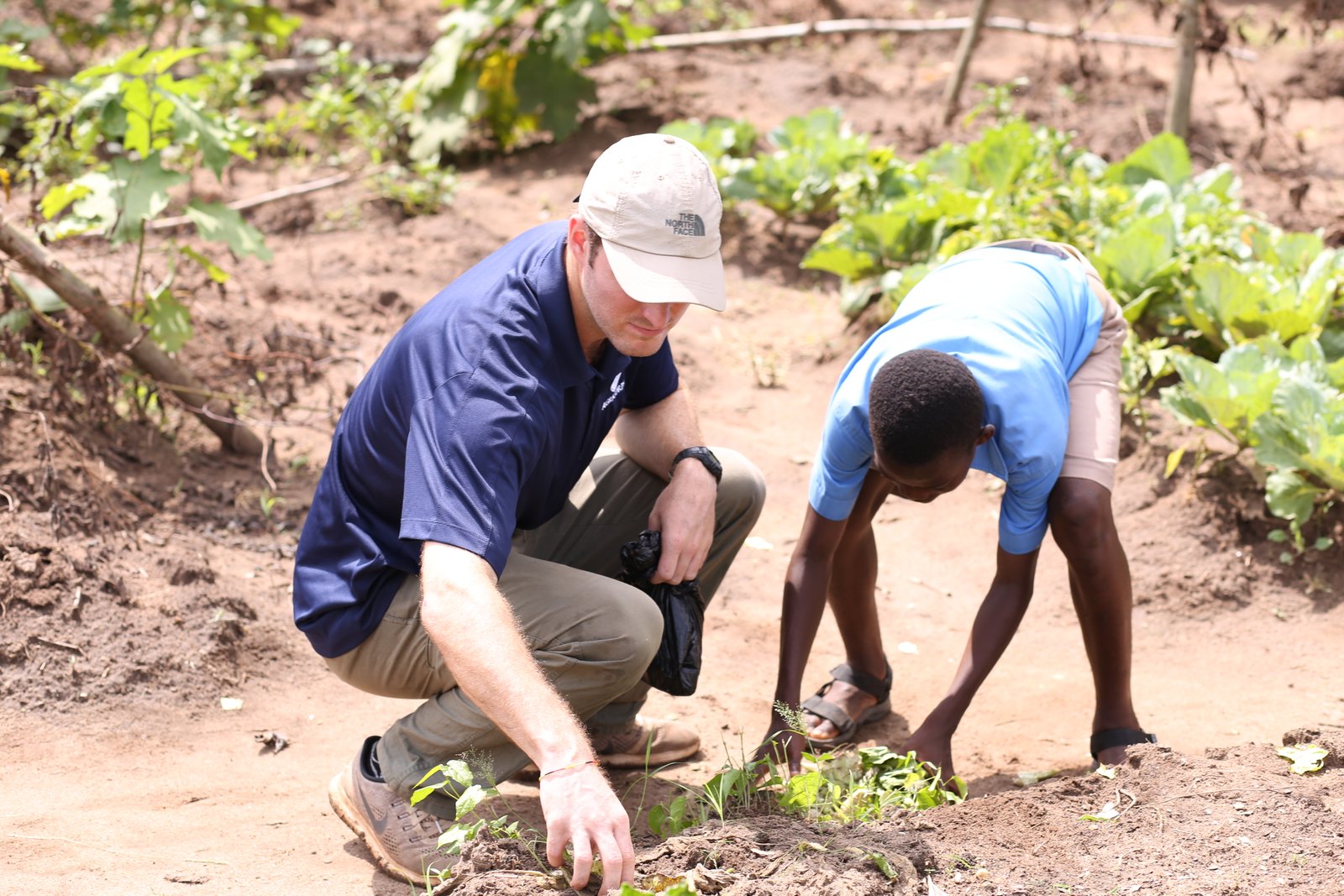 Ryan Tomlin and a student pull weeds
